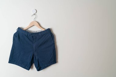 Kısa pantolon duvarda ahşap bir askıyla asılı.