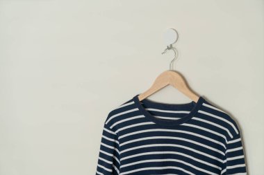 navy t-shirt hanging with wood hanger on wall