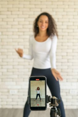 Latin kadın nüfuzlu kişi dans videosunu akıllı telefon kamerasıyla oluşturdu. Videoyu sosyal medya uygulamasına paylaşmak için.