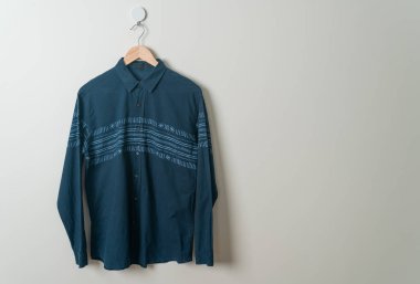 Duvarında ahşap askı olan donanma gömleği asıyor.