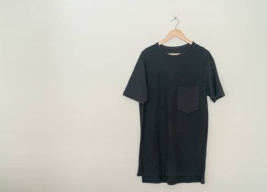 black t-shirt hanging with wood hanger on wall