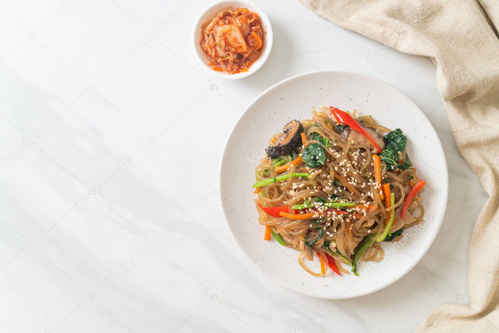 japchae or stir-fried Korean vermicelli noodles with vegetables and pork topped with white sesame - Korean traditional food style