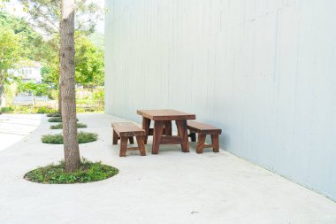 Boş ahşap teras masası ve beyaz duvarlı sandalye.