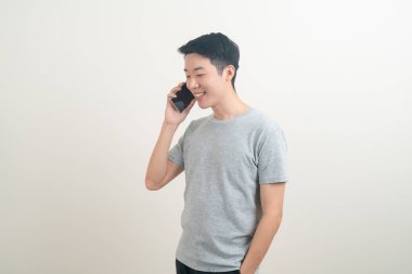 Beyaz arka planda akıllı telefon ve cep telefonu kullanan ya da konuşan genç Asyalı adam