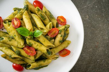 Pesto soslu ve domatesli makarna. Vejetaryen ve vejetaryen yemek tarzı.