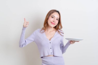 Beyaz arka planda boş tabak tutan güzel Asyalı kadın portresi