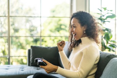 Laitin denen kadın evdeki kanepede elinde joystick ile video oyunları oynuyor.