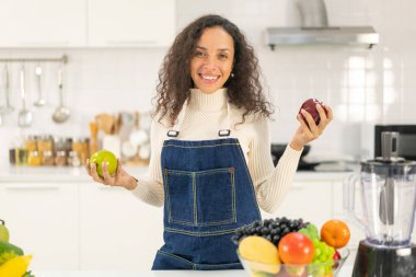 Latin kadın, vejetaryen yemeği için mutfakta meyve suyu yapıyor.