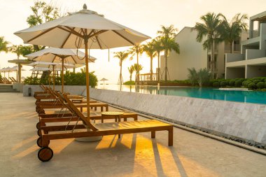 Okyanus geçmişi olan yüzme havuzunun etrafında havuzu olan şemsiyeler - tatil ve tatil kavramı