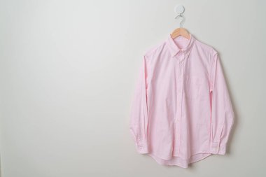 hanging pink shirt with wood hanger on wall