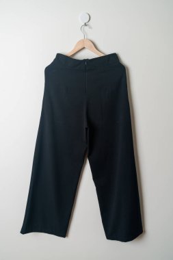 Pantolon ya da uzun pantolon duvarda ahşap askıyla asılı.