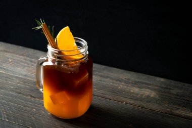 Bir bardak buzlu americano sade kahve ve biberiye ve tarçınla süslenmiş portakal ve limon suyu.