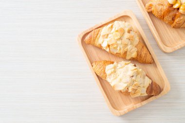 Kremalı kruvasan ve ahşap tabakta badem.