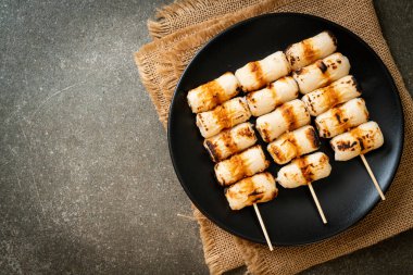 Izgara tüp şeklinde balık ezmeli kek ya da tabakta mürekkep balığı şişi.