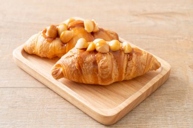 Macadamia ve ahşap tabakta karamel ile kruvasan.
