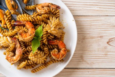 Deniz ürünleri ve fesleğen soslu kızarmış spiral makarna. Füzyon yemek tarzı.