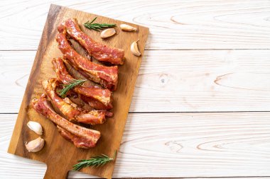 Tahtadaki malzemelerle birlikte kızartılmaya hazır taze çiğ domuz pirzolası.