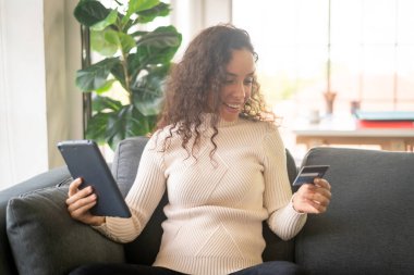 Tablet kullanan Latin bir kadın kredi kartı kullanıyor - İnternet üzerinden alışveriş kavramı