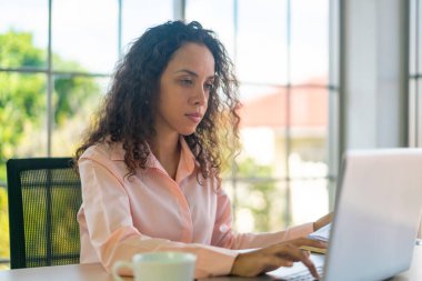 Latin kadın dizüstü bilgisayar ve kağıtlarla çalışıyor.