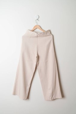 Pantolon ya da uzun pantolon duvarda ahşap askıyla asılı.