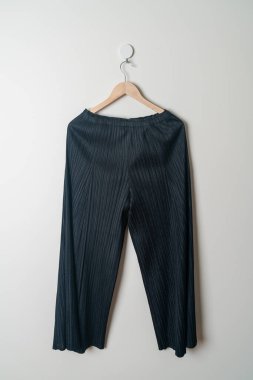 Pantolon ya da uzun pantolon duvarda ahşap askıyla asılı.