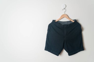Kısa pantolon duvarda ahşap bir askıyla asılı.