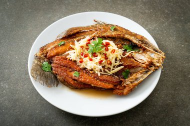 Balık soslu kızarmış deniz levreği balığı ve tabakta baharatlı salata.