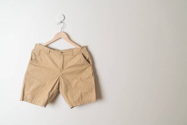 Kısa pantolon duvarda ahşap bir askıyla asılı.