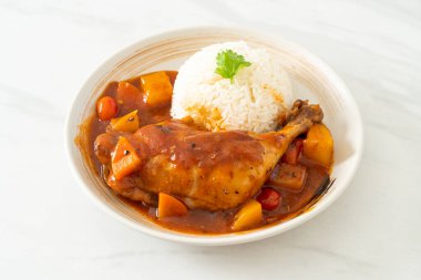 Domatesli ev yapımı tavuk güveci, soğan, havuç ve patates tabakta pilav.