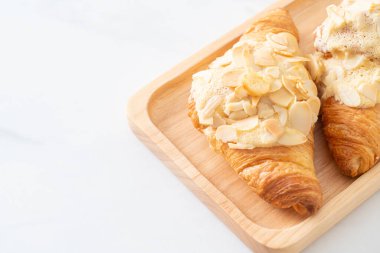 Kremalı kruvasan ve ahşap tabakta badem.
