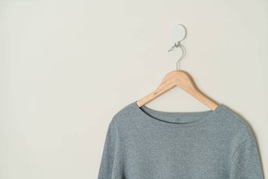 grey t-shirt hanging with wood hanger on wall