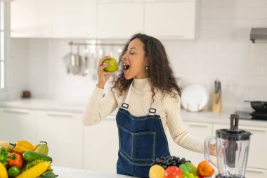 Latin kadın, vejetaryen yemeği için mutfakta meyve suyu yapıyor.