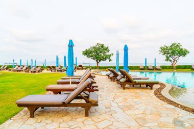 Tayland 'da Pattaya' da deniz plajı geçmişi olan havuz etrafında havuz ve şemsiye.