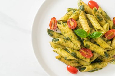 Pesto soslu ve domatesli makarna. Vejetaryen ve vejetaryen yemek tarzı.