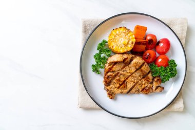 Izgara ve ızgara fileto domuz bifteği, mısır, havuç ve domates.