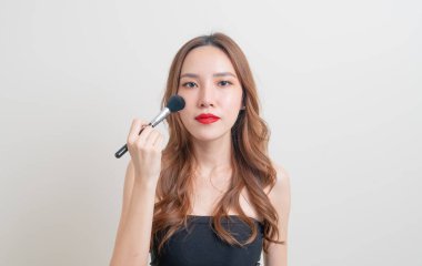 Beyaz arka planda makyaj fırçası olan güzel bir Asyalı kadın portresi
