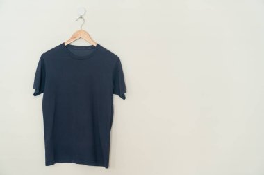 navy t-shirt hanging with wood hanger on wall