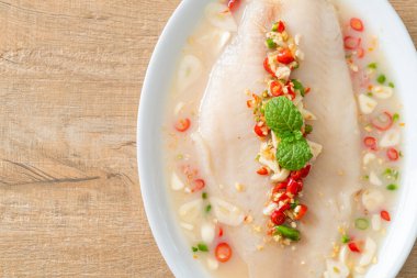 Beyaz tabakta baharatlı limon soslu balık.