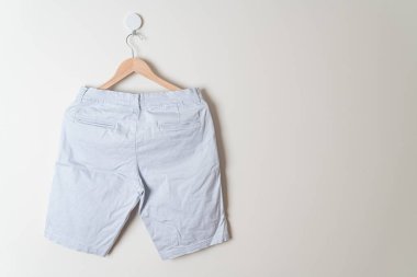 Kısa pantolon duvarda ahşap bir askıyla asılı.