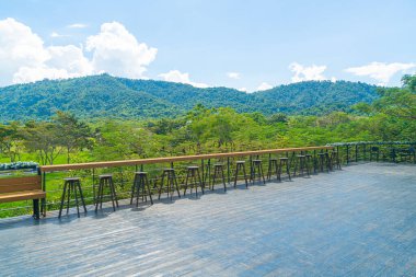 Balkonda boş bir bank ve bar taburesi var.