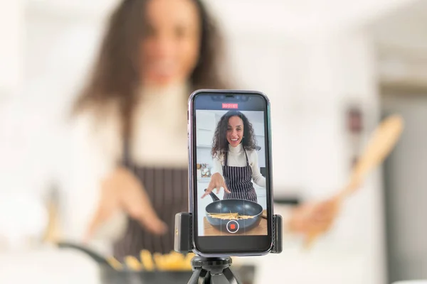 Latin kadın blogda paylaşmak için mutfakta video ve yemek çekiyor.