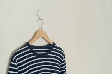 navy t-shirt hanging with wood hanger on wall