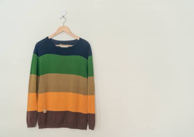 colorful sweater hanging with wood hanger on wall