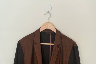 dark brown suit hanging with wood hanger on wall