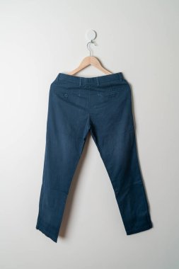 Pantolon ya da uzun pantolon duvarda ahşap askıyla asılı.