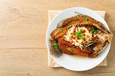 Balık soslu kızarmış deniz levreği balığı ve tabakta baharatlı salata.