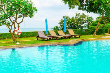 Sandalye havuzu ve şemsiyeyle okyanus arka planında yüzme havuzu