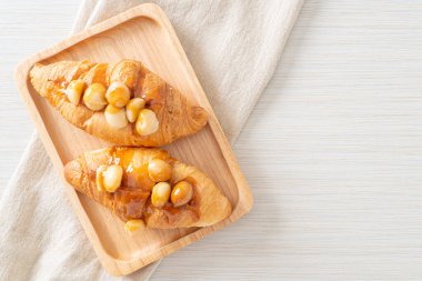 Macadamia ve ahşap tabakta karamel ile kruvasan.