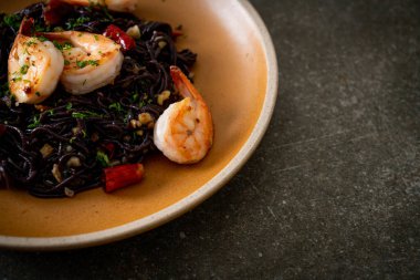 Sarımsaklı ve karidesli kızarmış siyah spagetti.