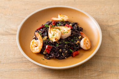 Sarımsaklı ve karidesli kızarmış siyah spagetti.